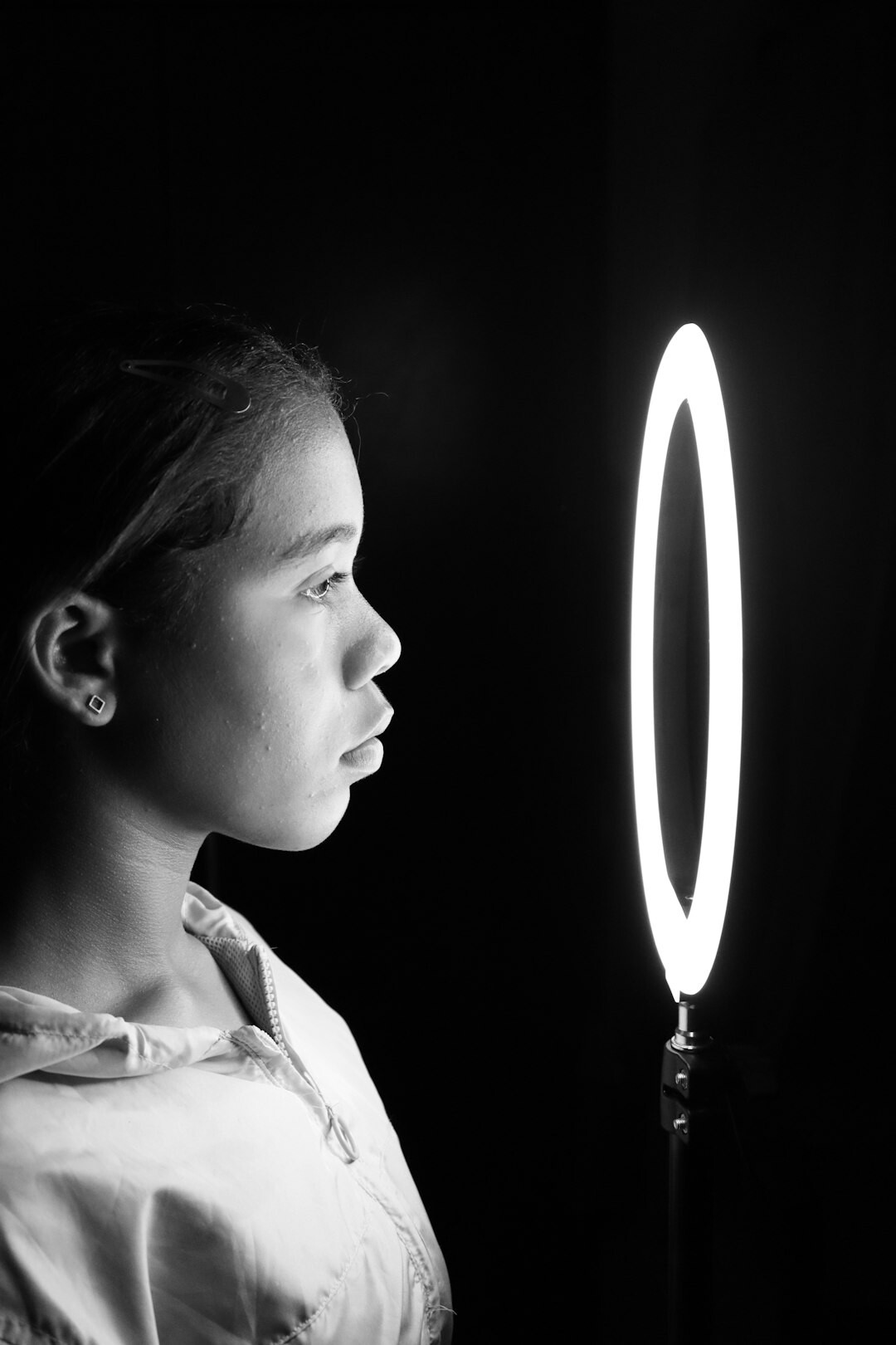 Young woman filming vertical video with smartphone and ring light